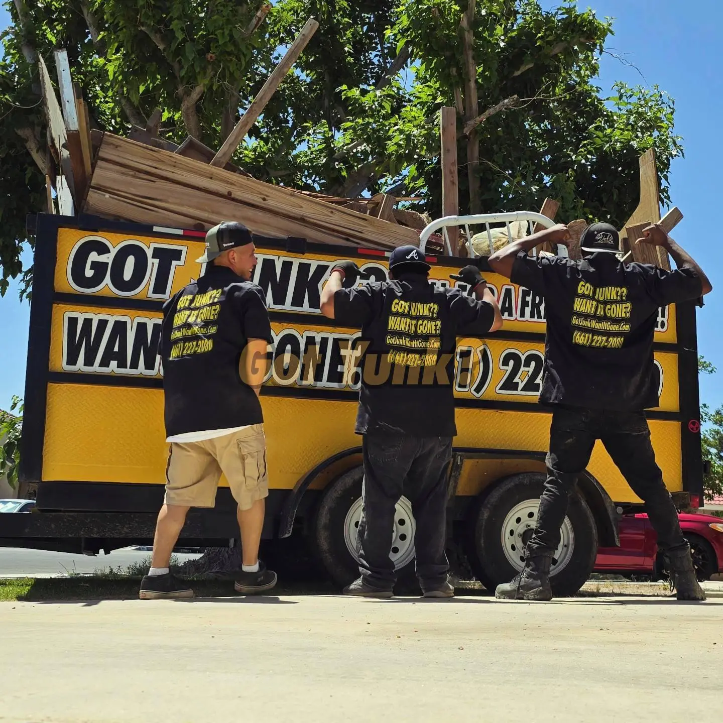Back of junk removal team uniforms showing branding and phone number in Palmdale, CA. Got Junk? Want It Gone? crew.