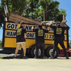 Crew showing off branded uniforms next to junk trailer in Quartz Hill.