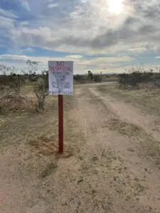 No trespassing sign posted on private land cleanup site in Palmdale desert area.
