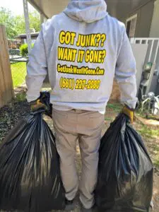 Worker hauling full garbage bags for disposal in Santa Clarita, CA.
