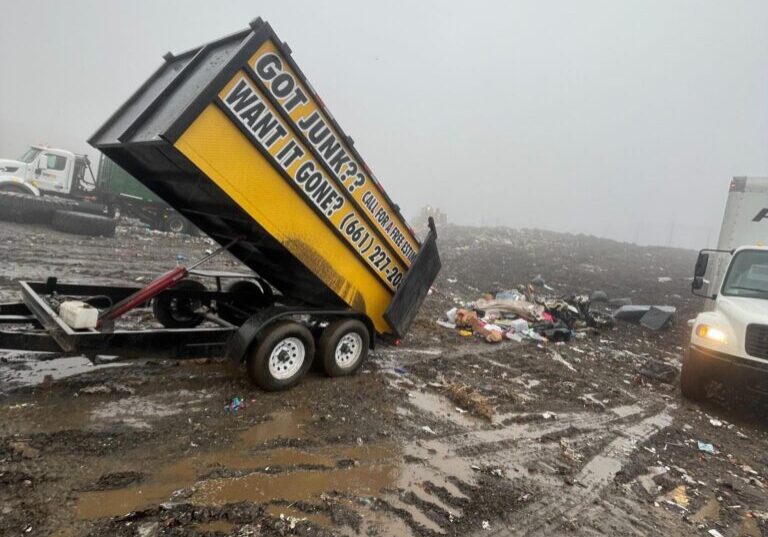 Dump trailer unloading junk at a muddy landfill in Lancaster, CA.